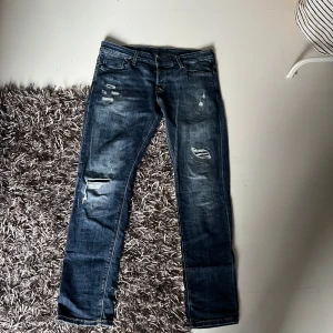 Blå slitna jeans Jack & Jones Slim/Glenn - Snygga blå jeans från Jack & Jones i modellen Slim/Glenn. Passar inte längre, storlek 34/32. Blivit en lite sliten mellan benen men syns knappt 