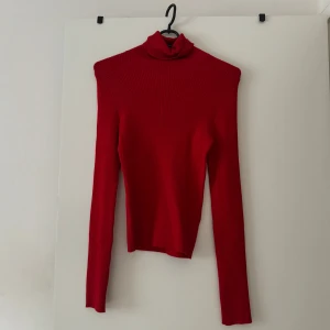 Röd ribbad polotröja från H&M - Snygg röd polotröja från H&M Divided i storlek S. Tröjan är ribbad, har lång ärm och en tight passform som sitter riktigt bra. Perfekt att styla med jeans eller kjol för en trendig look. Materialet är mjukt och stretchigt för extra komfort.