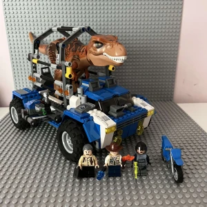 LEGO Jurassic World: T-Rex Transport - LEGO Jurassic World T. rex Breakout (75918) – Komplett, Byggt en gång, Som nytt  Säljer ett komplett LEGO Jurassic World-set, modell 75918 T. rex Breakout. Detta inkluderar den stora T. rex-figuren, 3 minifigurer, ett blått fångstfordon med avtagbar bur, motorcykel, datorstation och alla tillbehör som syns på bilderna.  Setet har byggts en gång och stått framme, aldrig lekts med, bitarna och klistermärkena är i utmärkt skick. Instruktionsböckerna (båda delarna) ingår. Inga saknade bitar.  