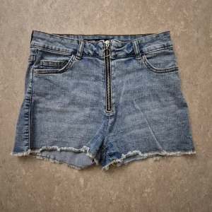 Jeansshorts - Snygga jeansshorts från FB Sister i ljusblå denim. De har råa, fransiga benslut och en cool dragkedja framtill. Klassisk femficksmodell med bälteshällor och bakfickor. Perfekta för sommaren!
