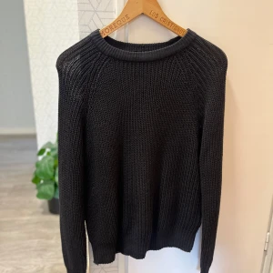 Svart stickad tröja Black Label L - En svart stickad tröja från The Black Label Collection i storlek L. Tröjan har grovstickad struktur, rund halsringning och långa ärmar. Perfekt för dig som gillar en enkel och stilren look med lite oversized känsla.