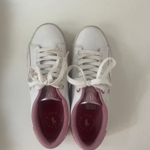 Slutsålda skor från Ralph lauren - Vita sneakers med rosa glittriga detaljer. Skorna är slutsålda på de flesta hemsidor. Dem är från barnavdelningen i storlek 40, men skulle säga att dem är mer som 39. Endast använda en gång!! 