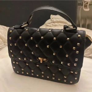 Svart valentinoväska med guldnitar - Snygg svart valentino väska med guldiga  nitar över hela väskan. Bra skick. Säljer extremt billigt eftersom jag flyttar snart. Onesize.