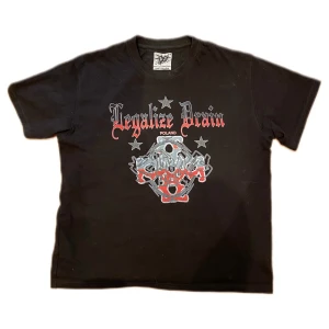 Drain Gang ”Legalize Drain” Bladee Merch  - Svart t-shirt från Drain Gang med stort grafiskt tryck och texten 'Legalize Drain' på bröstet. Coola stjärndetaljer och unikt motiv både fram och bak. Klassisk passform och rund hals. Perfekt för dig som gillar streetwear och edgy stil.