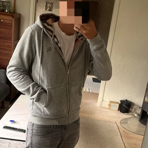 Grå zip Burberry - Grå hoodie från Burberry med dragkedja, klassisk rutig huva och broderad logga på bröstet. Skick: 10/10, Storlek S, hör gärna av er vid frågor, Mvh