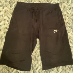 Svarta shorts från Nike med snörning M/L - Svarta shorts från Nike med klassisk logga på vänster ben. Mjukt material och bekväm passform, perfekta för träning eller chill. Utrustade med snörning i midjan och två sidofickor. Enkla att matcha med det mesta. Använda max 2-3 gånger. Storlek M passar också de som har L.