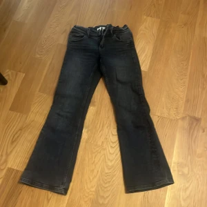 Svarta bootcut jeans från Gina Young str 152 - Snygga svarta jeans från Gina Young str 152 i bootcut-modell med justerbar midja och dragkedja. Jeansen har bakfickor med lock och silverfärgade knappar. 