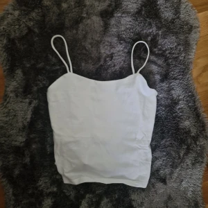 Vit linnetopp från XOXO friends - Säljer en enkel och stilren vit linnetopp från XOXO friends i storlek 158/164. Toppen har tunna axelband och rak skärning, perfekt för varma dagar eller som lager under skjorta. Gjord i mjuk bomull som känns skön mot huden.