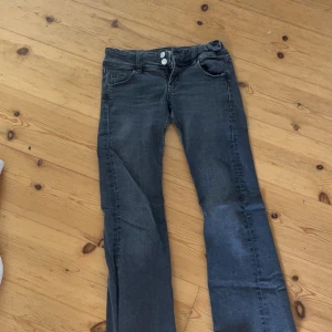 Grå bootcut jeans från Gina Tricot - Säljer ett par grå jeans från Gina Tricot i storlek 146. Jeansen har bootcut-modell, klassiska femficksdetaljer och dubbla knappar i midjan. Snygg tvätt och sköna att bära, perfekta till sneakers eller boots.