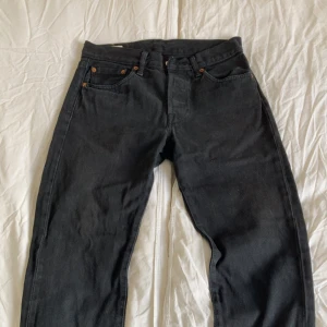Levi's 501 svarta jeans W28 L32 - Klassiska svarta jeans från Levi’s – tidlös design med hög kvalitet. Jeansen har en smal och snygg passform, perfekt för både vardags- och lite mer uppklädda tillfällen.  🖤 Färg: Svart 📏 Storlek: W28 / L32 👖 Modell: straight 🧵 Material: Bomull med lätt stretch 📦 Skick: Mycket bra skick – inga hål, fläckar eller slitningar  Ett par mångsidiga jeans från ett klassiskt märke – passar till allt!