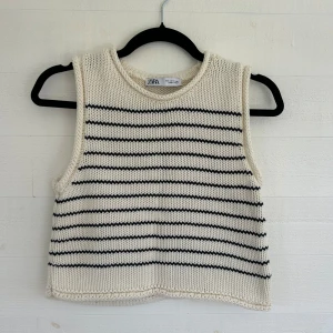 Randig stickat linne från Zara - Superfin stickat linne från Zara i vitt med svarta horisontella ränder. Modellen är ärmlös med rund halsringning och har en lite boxig, croppad passform. 