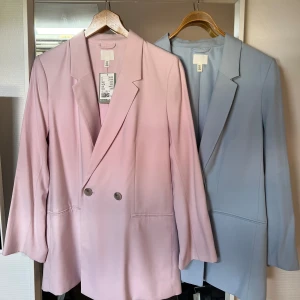 H&M Kavajer - H&M kavajer (samma modell) köpta för några år sedan. Den rosa kavajen har sin prislapp kvar och är endast testad. Den blåa kavajen är endast använd vid ett tillfälle. Rosa kavajen helt oanvänd med prislapp kvar (värde 349 kr), säljes för 220 kr. Blå kavaj använd 1 gång, 180 kr. 350 kr för båda.