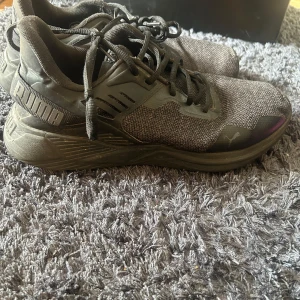 Svarta sneakers från Puma - Snygga svarta sneakers från Puma med stickad ovandel och robust sula. Skorna har snörning och diskreta Puma-loggor på sidan och hälen. Perfekta för dig som gillar en sportig och stilren look.