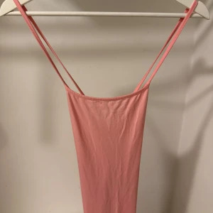 Rosa klänning  med smala axelband - En enkel och stilren rosa klänning med smala axelband. Klänningen har en rak passform och ärmlös design, perfekt för varma dagar. Mjuk och lätt i materialet, vilket gör den superbekväm att bära.