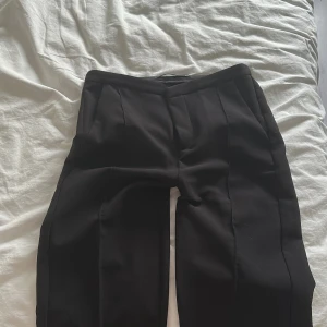 Svarta bootcut kostymbyxor, Gina Tricot XS - Svarta kostymbyxor från Gina Tricot i storlek XS. Byxorna har pressveck framtill, snedställda fickor och en enkel bakficka. Klassisk bootcut passform och lagom i midjan, perfekta till en snygg look. Materialet är mjukt och bekvämt. 