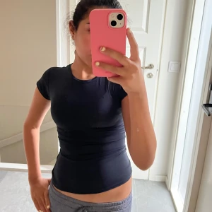 mörkblå tight kortärmad topp - säljer en blå tight topp med korta ärmar. Enkel och stilren design utan mönster, perfekt att styla med olika outfits. Tunt och stretchigt material som sitter snyggt mot kroppen och ger en sportig vibe. 