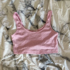 Rosa ribbad linnetopp från H&M Divided - Säljer en ljusrosa ribbad linnetopp från H&M Divided. Toppen är ärmlös med breda axelband och croppad passform, perfekt till sommaren. Mjuk och stretchig bomullskvalitet som sitter skönt mot kroppen.