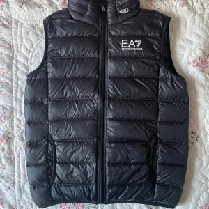 EA7 väst - En Armani väst som är i riktigt bra skick, ungefär helt ny, använd runt 10 ggr, är i storlek S men kan passa XS också, det finns en lite luva som man kan ta ut från nacken som man ser på bild 3, tveka inte att fråga om något!!!