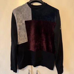 Blockmönstrad tröja från Vichy - Snygg långärmad tröja från La Vichy i färgen vinrött, mörkblått och grått sammetstyg framtill. Svarta ärmar och rygg. Tröjan är i storlek S 