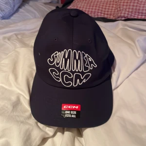 Svart keps från CCM med brodyr - Svart keps från CCM med vit broderad text 'SUMMER CCM' framtill. Klassisk böjd skärm och justerbart spänne bak för perfekt passform. Kepsen är i one size och tillverkad i ett slitstarkt material som passar till sommaren.