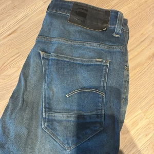 Blå jeans från G-Star RAW - Säljer ett par klassiska blå jeans från G-Star RAW. De är slim/ straight i passformen. De är i storlek 31w 32L. De finns lite  små slitage. Hör av er om ni är intresserade eller har frågor. Pris kan diskuteras vid snabb affär ! 