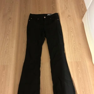 Svarta bootcut jeans - Säljer ett par svarta jeans med bootcut-modell. Byxorna har klassisk femficksdesign och stängs med knapp och dragkedja. Perfekta för dig som gillar en tidlös look med lite utsvängda ben. Inte fri frakt! 