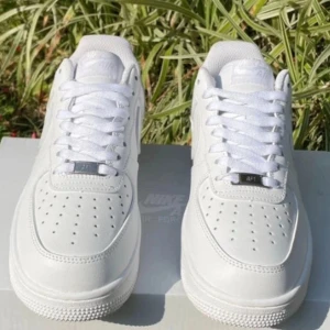 Nike Air Force 1  - Klassiska Nike Air Force 1 sneakers i helvitt skinn med vit sula och snörning. Ikonisk siluett med perforerad tå och broderad Nike-logga på hälen. Perfekta för dig som vill ha en clean och tidlös look till vardags. Nypris på ca 1200SEK/ Mitt pris 899 SEK box kommer med!