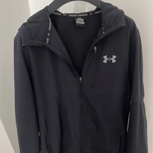 Svart vindjacka från Under Armour - Under Armour vindjacka i storlek S. Nypris 1200. Skick är 10/10 helt ny knappast använd. Pris kan diskuteras.