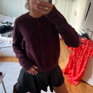 Vinröd kofta med knappar - Säljer en mysig vinröd kofta med rund hals och knäppning framtill. Koftan är långärmad och har en enkel, klassisk design som passar perfekt till lager-på-lager. Materialet känns mjukt och lite fluffigt, perfekt för kyligare dagar. Passar xs-m!❤️❤️❤️