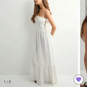 Vit långklänning från Nelly - Superfin vit långklänning från Nelly med smockad överdel, tunna axelband och volangkant nertill. Klänningen har knyt i sidorna och kan bäras både med och utan axelband. Perfekt för varma dagar och somriga vibes. Helt ny, säljer då den inte kommer till användning💕 Nypris 699:-