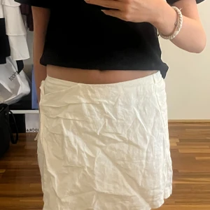 Vit omlottkjol/shorts i linne från Zara - Superfräsch vit omlottkjol från Zara i luftig linnemix. Kjolen har knytband i sidan och är kort, perfekt för varma dagar. Enkel och stilren design som passar till allt. Säljs i storlek 152. Det är typ ett par shorts med en framsida som en kjol. Prislapp kvar. 