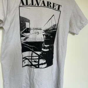 Vit t-shirt med tryck från Allvaret - Merch från bandet Allvaret. Klassisk passform och rund hals. Tillverkad i bomull.