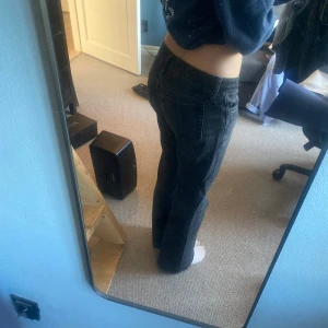 Svarta bootcut jeans - Säljer ett par svarta bootcut jeans med klassisk femficksdesign och låg midja. Jeansen har en lätt tvättad look och är tillverkade i denim. Är lite slitna längst ner men det är inget man märker så mycket.