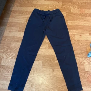 Mörkblå mjukisbyxor från ONLY - Mörkblå mjukisbyxor från ONLY med dragsko i midjan och smal passform. Byxorna har elastisk midja, sidofickor fram och fuskfickor bak. Perfekta för en chill och avslappnad stil.