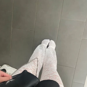 Vita spetsbyxor med bootcut - Säljer ett par vita byxor i genombruten spets med snygg bootcut-modell. Byxorna har hög midja och är stretchiga för en bekväm passform. Perfekta för dig som vill sticka ut med en trendig och feminin look.