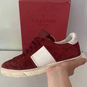 Valentino Flycrews - Snygga vinröda sneakers från Valentino Garavani i mocka med vita detaljer och vit sula. Klassisk låg modell med snörning och rund tå. Perfekta för dig som vill ha en exklusiv och stilren look med streetkänsla. Nypris 7000, pris går att diskutera.