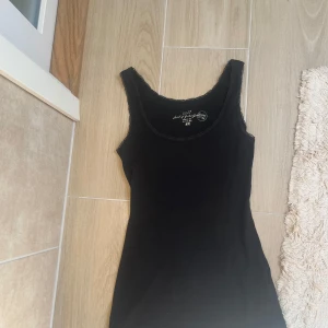 Svart linnetopp från H&M L.O.G.G. - En svart linnetopp från H&M L.O.G.G. i mjuk bomullsmix med 3% elastan för extra stretch. Toppen har smala axelband, rundad halsringning och diskret spetskant runt hals och ärmhål. Perfekt att styla lager på lager eller som den är. Skulle säga är mer åt S-hållet även om den säger att den ska vara storlek M. Knappt använd!🩵