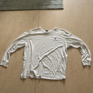 Vit långärmad tröja Polo Ralph Lauren - Vit långärmad tröja från Polo Ralph Lauren i 100% bomull. Klassisk passform med rund hals och broderad marinblå logga på bröstet. Perfekt basic-plagg med stilren look och mjukt material.