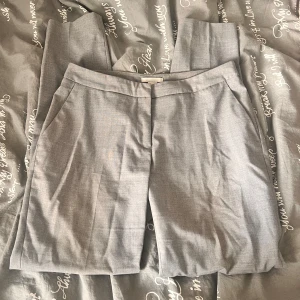 Ljusgrå kostymbyxor med raka ben - Snygga ljusgrå kostymbyxor med klassisk rak passform och pressveck. Byxorna har sidfickor fram och en diskret bakficka. Perfekta för en clean och stilren look. Materialet känns lätt och dressat.