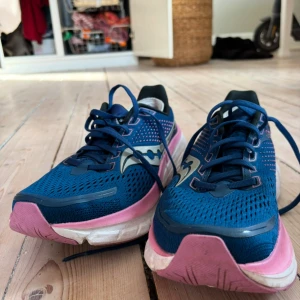 Blå Saucony löparskor i stl 40,5. Modell: guide 17 - Snygga löparskor från Saucony i storlek 40,5, modell guide 17 i blått och rosa. Perfekt för löprundan eller en promenad. Använda ett fåtal gånger bara då de är för stora för mig. 