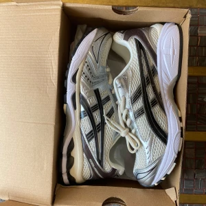 ASICS Gel-Kayano 14 sneakers silver/vit - Snygga ASICS Gel-Kayano 14 sneakers i silver och vitt med svarta detaljer. Ovandel i mesh och syntet, klassisk snörning och chunky sula för grym komfort. Perfekta för dig som gillar retrovibbar och sportig stil. Storlek 42.5 men dem passar till 41/41.5. Priset kan diskuteras vid snabb affär 