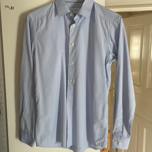 Ljusblå skjorta från Eton i storlek 38 slim  - En kostymskjorta från den välkända svenska skjortproducenten Eton i storlek 38 slim (s/m). Skjortan är använd 2-3 gånger men så gott som ny utan några alls defekter.