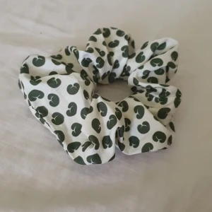 Vit scrunchie med grönt mönster - En söt scrunchie i vitt tyg med gröna, abstrakta prickar. Perfekt accessoar för att piffa upp håret och ge en lekfull touch till din look.