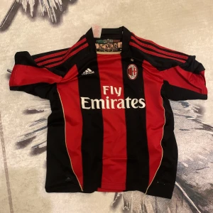 AC Milan Ibrahimović matchtröja Adidas - Säljer en klassisk AC Milan fotbollströja från Adidas med Ibrahimović och nummer 11 på ryggen. Tröjan är röd och svart med vertikala ränder, klubbmärke på bröstet och Fly Emirates 