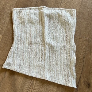 Beige strukturerad tubtopp NA-KD - Säljer en beige tubtopp med snyggt strukturerat material. Den är snedskuren längst ner. Knappt använd. 