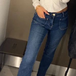 Mörkblå bootcut jeans med hög midja - Säljer ett par mörkblå jeans med bootcut och hög midja. Jeansen har stora framfickor, klassisk gylf med knapp och är tillverkade i stretchig denim. Snygg passform som sitter tajt upptill och släpper vid benen.
