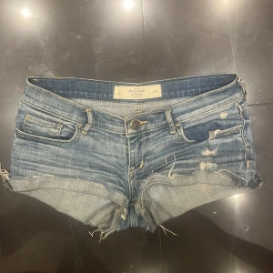 Blå low waist jeansshorts Abercrombie & Fitch - Snygga blå low waist jeansshorts från Abercrombie & Fitch med slitna detaljer och fransiga kanter!!💋 passar nu till sommaren då dom är skit snygga och jätte sköna!! dom har använts ungefär 2-3 gånger och säljs pga dom inte kommer till användning!💞 Köptes för 400kr och säljs för 370kr pris kan absolut diskuteras vid jätte snabbt köp!!