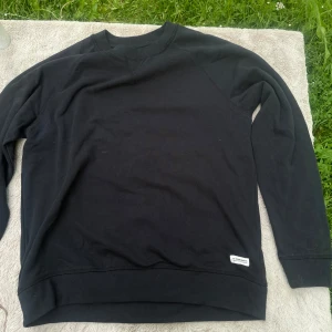 Svart sweatshirt från 157 Denim Makers - En stilren svart sweatshirt från 157 Denim Makers med rund hals och diskret logga nertill. Tröjan har långa ärmar och är tillverkad i mjuk bomull, perfekt för chill dagar eller när du vill ha en clean look.