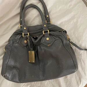 Grå Marc Jacobs väska - Säljer min Marc Jacobs väska då den inte kommer till användning. Den är vintage och har en del små defekter (se bilderna). Mellanstor modell och så rymlig! 