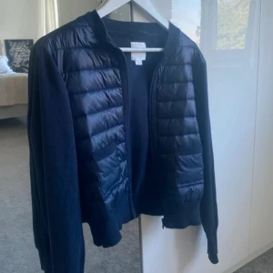 Mörkblå quiltad cardigan jacka - Snygg mörkblå cardigan jacka med quiltade partier framtill och på axlarna. Jackan har dragkedja, ribbade muddar och två praktiska fickor. Perfekt för lager-på-lager och chill vardagsstil. Storlek 164